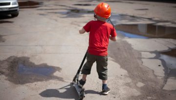 little boy riding a razor scooter