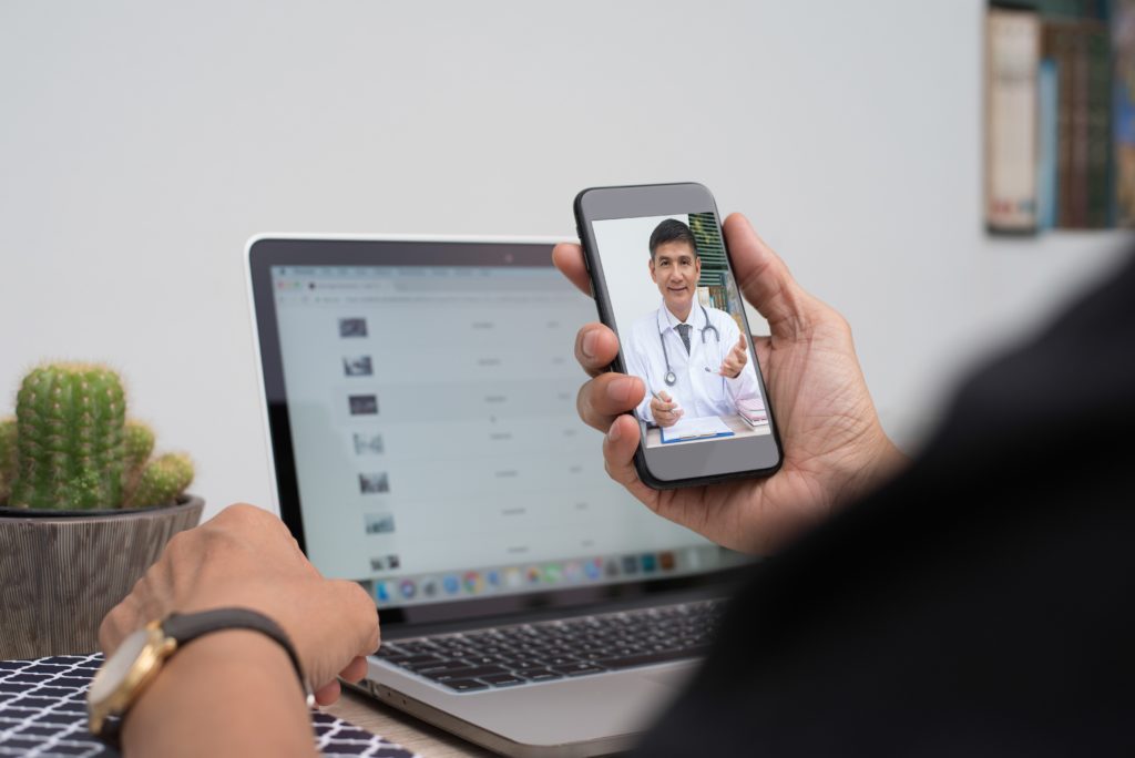 student using telemedicine on their cellphone while working at desk
