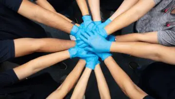 hands stacked together wearing protective gloves