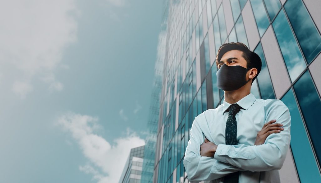 man wearing mask in front of office building
