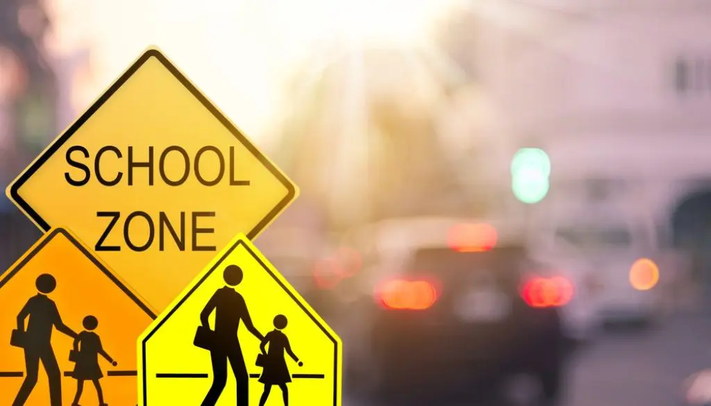 school crosswalk signs with traffic in background
