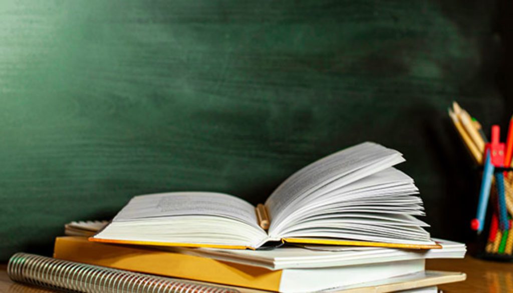 open text book on desk in front of blackboard