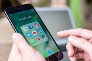 hand using cell phone with social media folder open