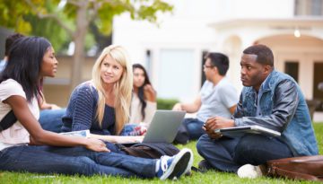 group of university students sitting in grass