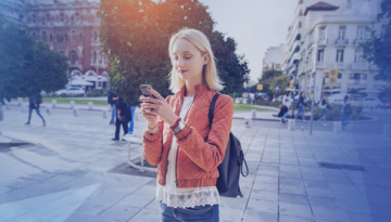 woman holding phone walking street