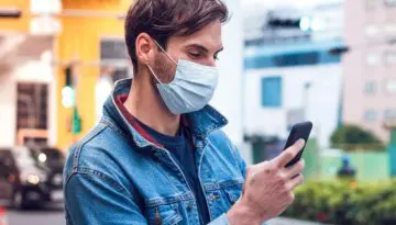 man on phone outside wearing mask