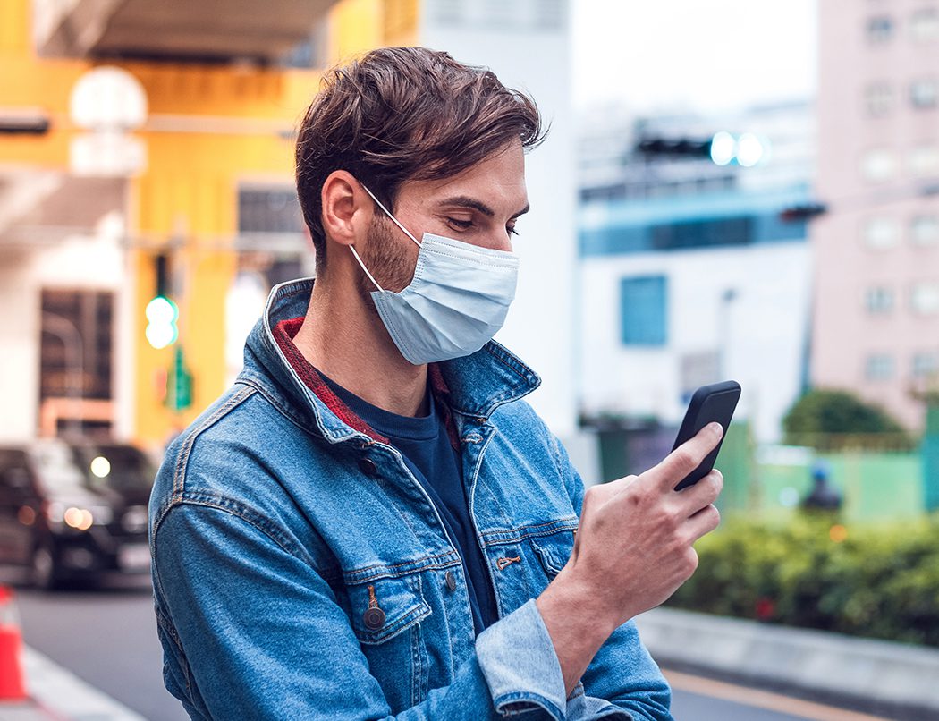 man on phone outside wearing mask