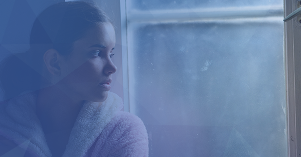 woman looking out window solemn mental health blue overlay background