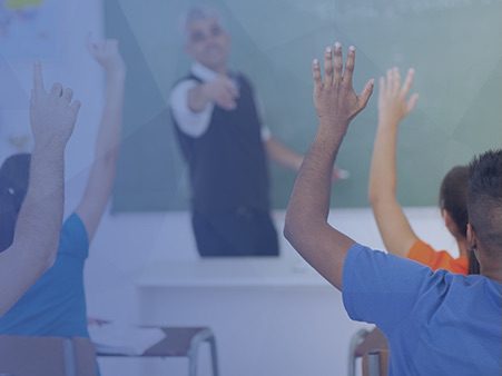 students in a classroom with hands raise and teacher pointing at students