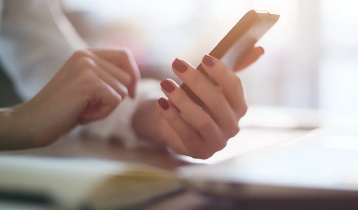 hand holding cell phone on a desk