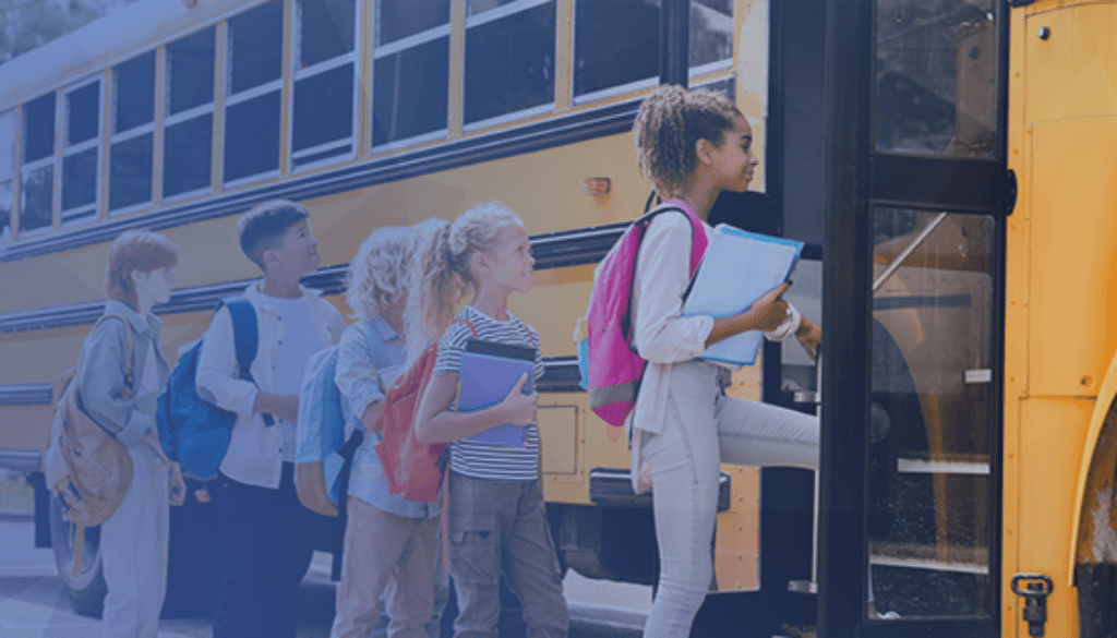 school kids with backpacks and binders lined up and boarding a yellow school bus