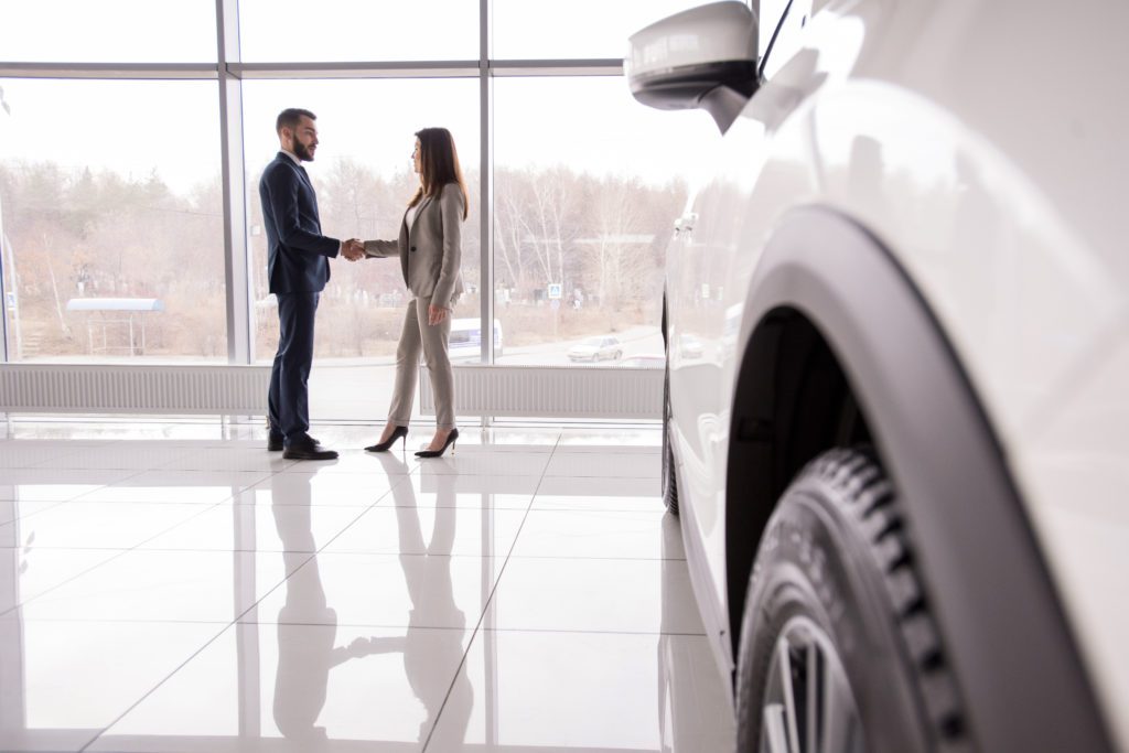 man and woman in a car dealership shaking hands