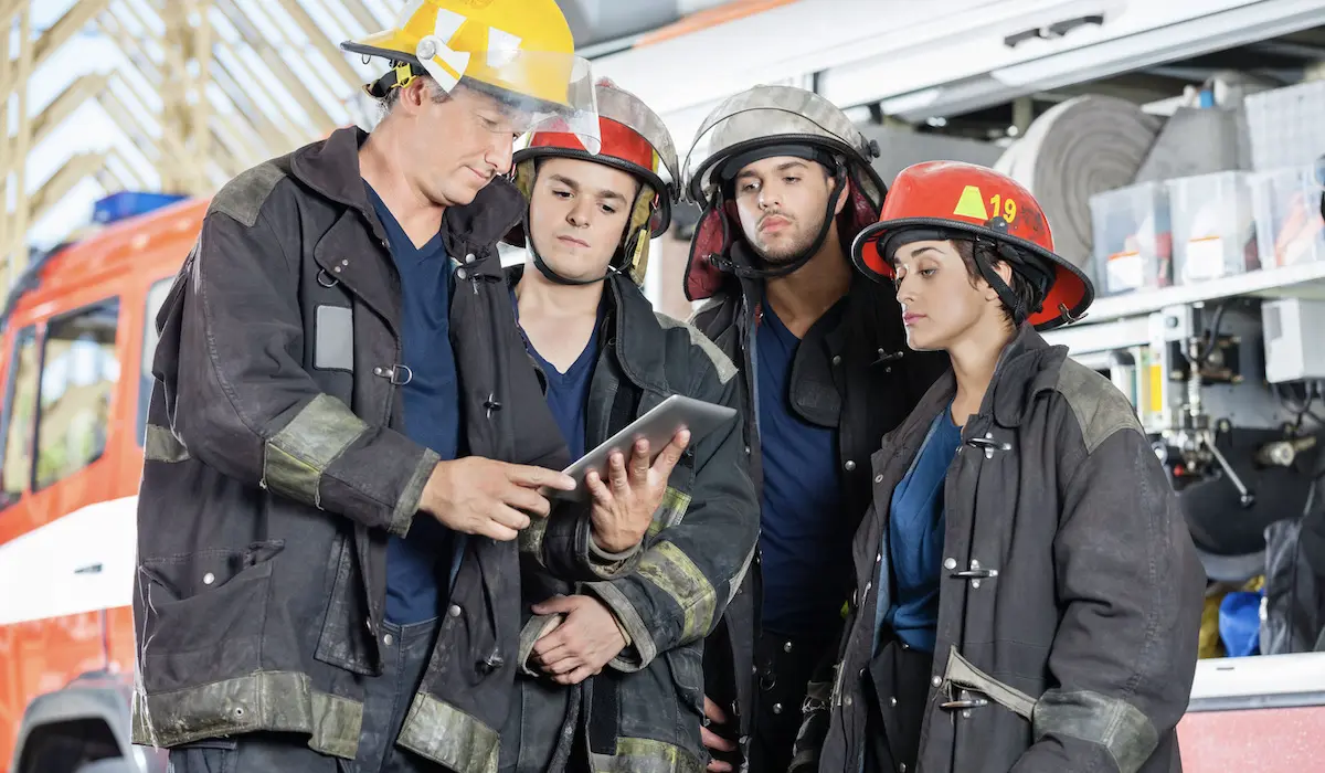 group of first responders standing outside building looking at a tablet together