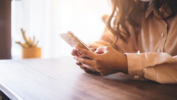 woman typing on her phone wearing a face mask