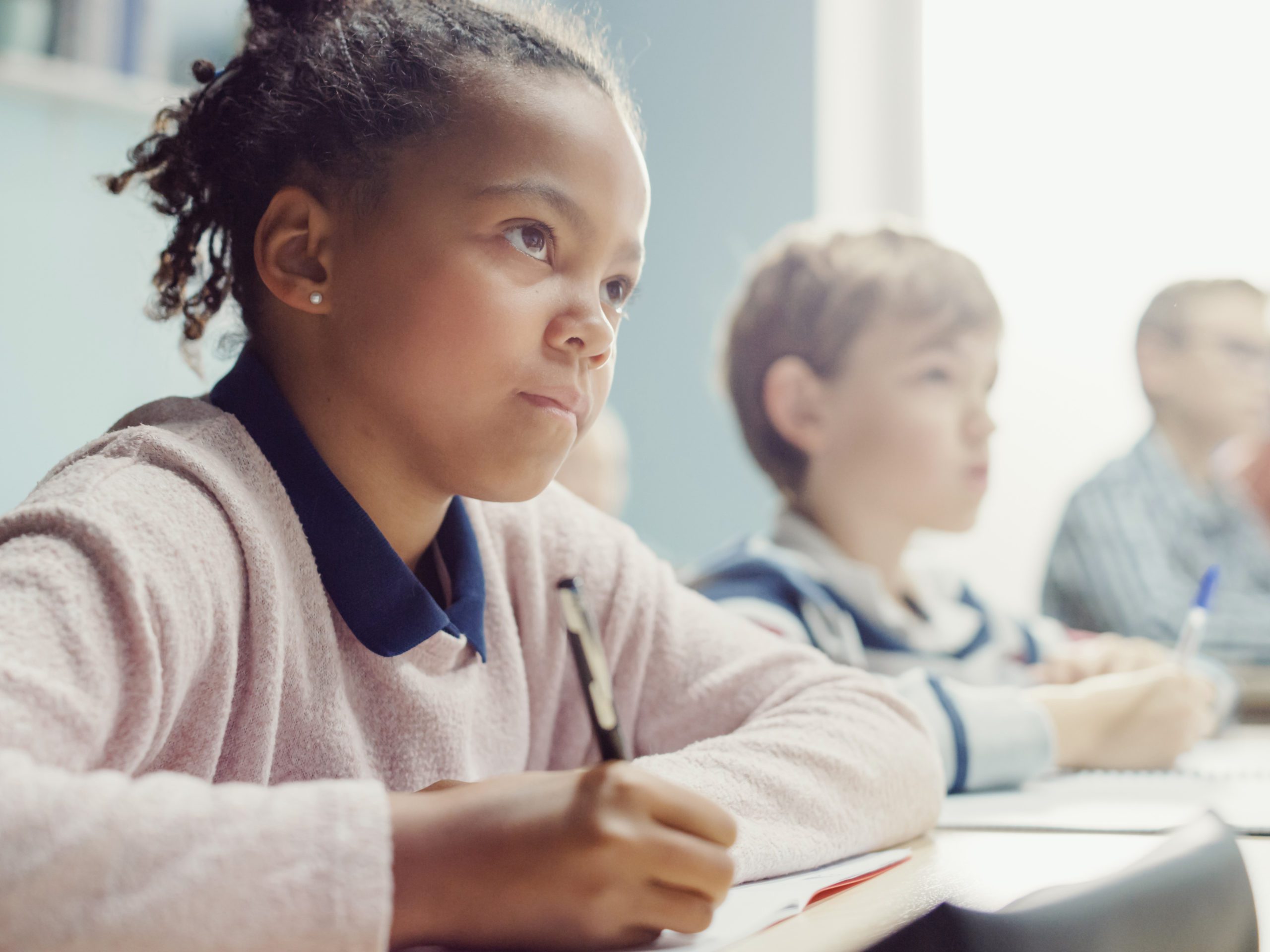 elementary school student girl in classroom taking note