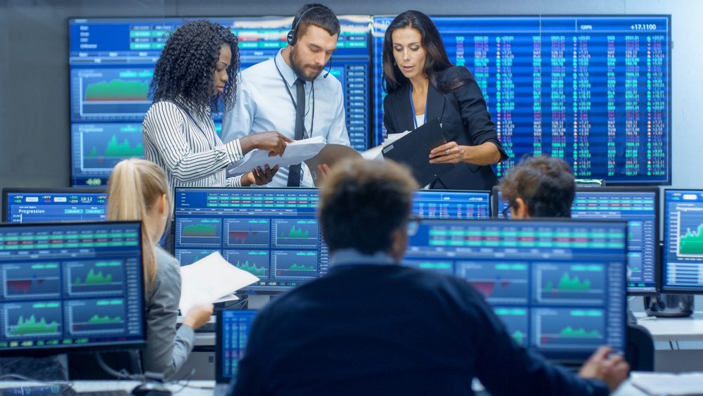 group of employees working in financial services in a room with computer monitors