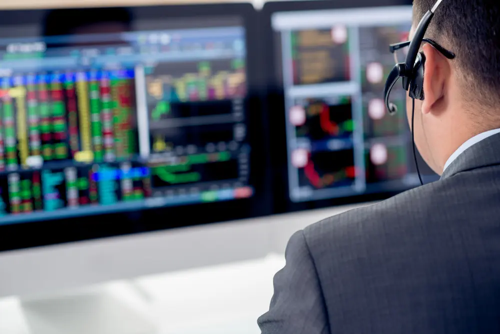 man working at desk looking at financial figures on screen