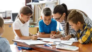 teacher in classroom helping young students