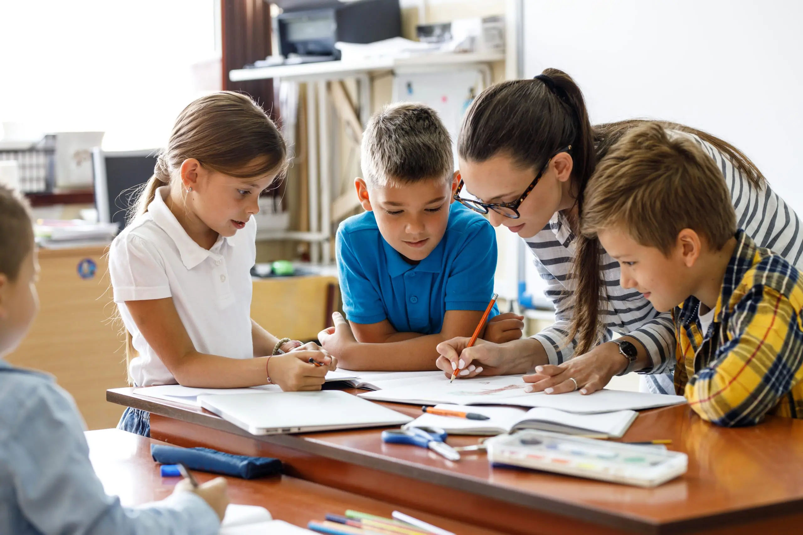 teacher in classroom helping young students