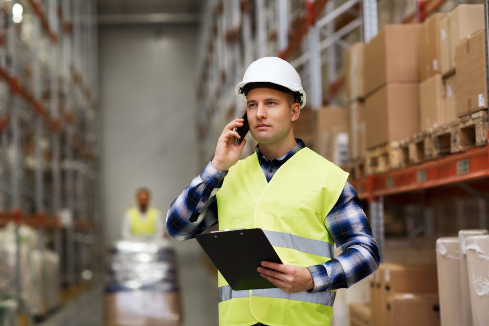 warehouse-worker-phone-clipboard warehouse worker holding a clipboard talking on phone