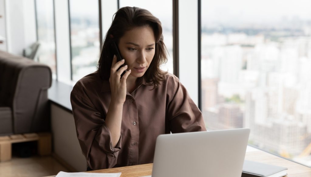 woman answering phone tree automated call working on a laptop