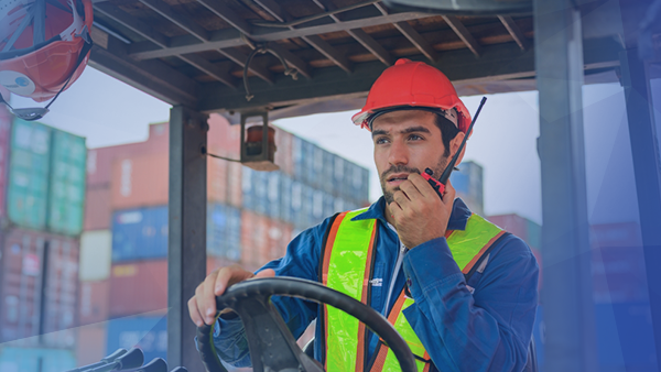 man driving forklift using walkie talkie