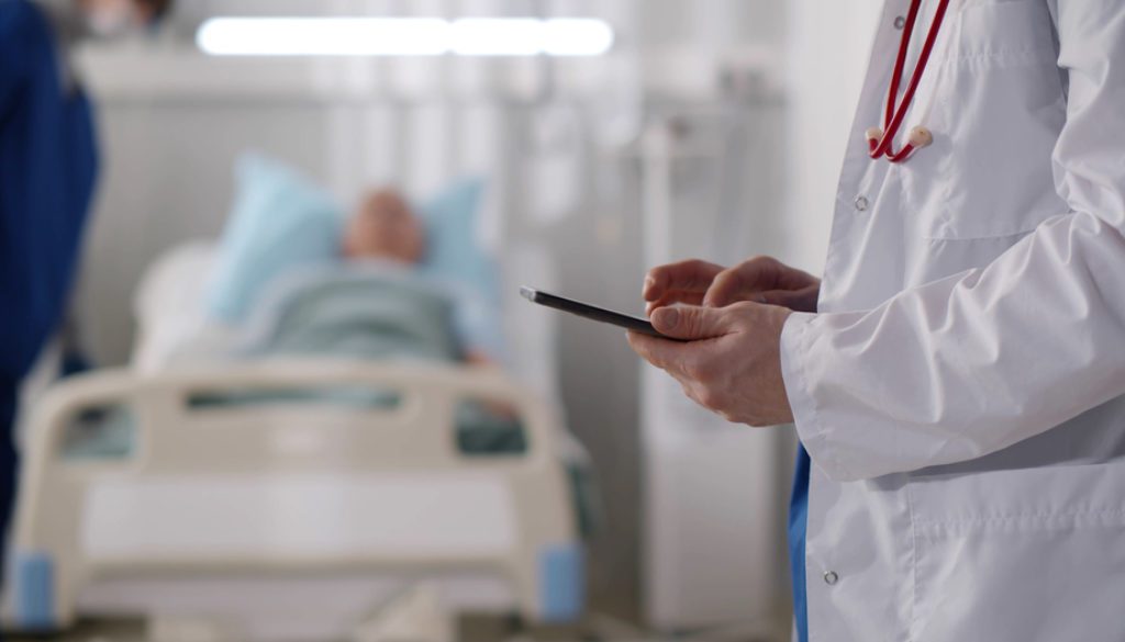 doctor looking at phone with patient in background