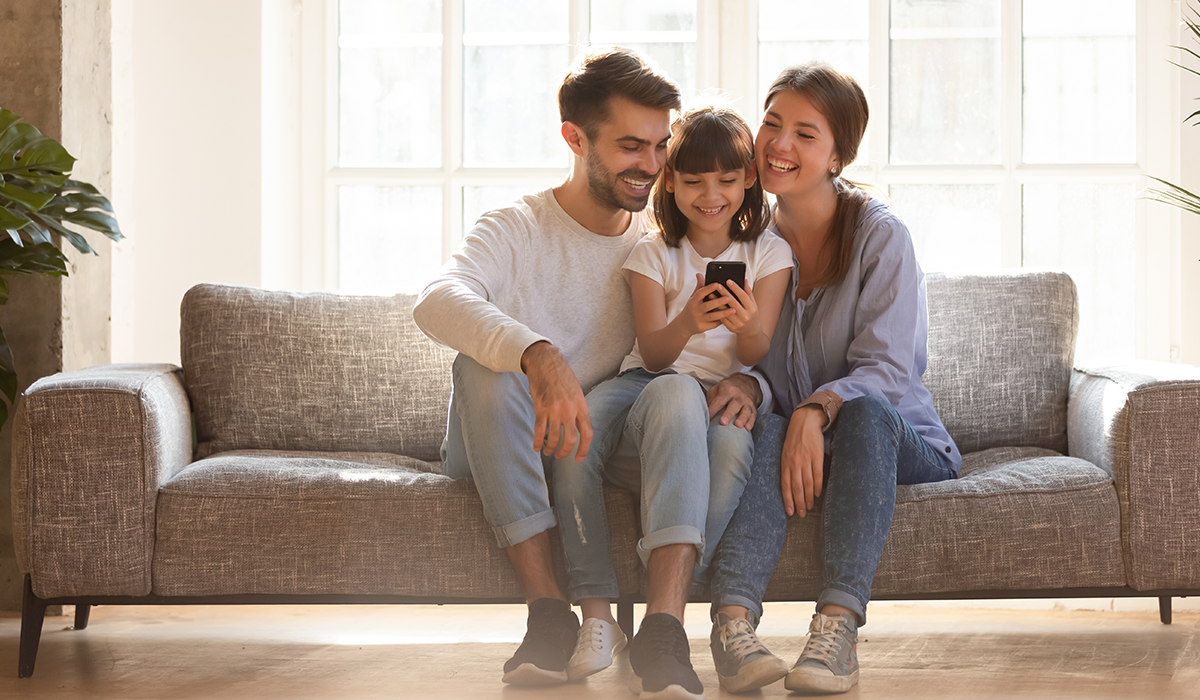 family sitting on couch looking at phone