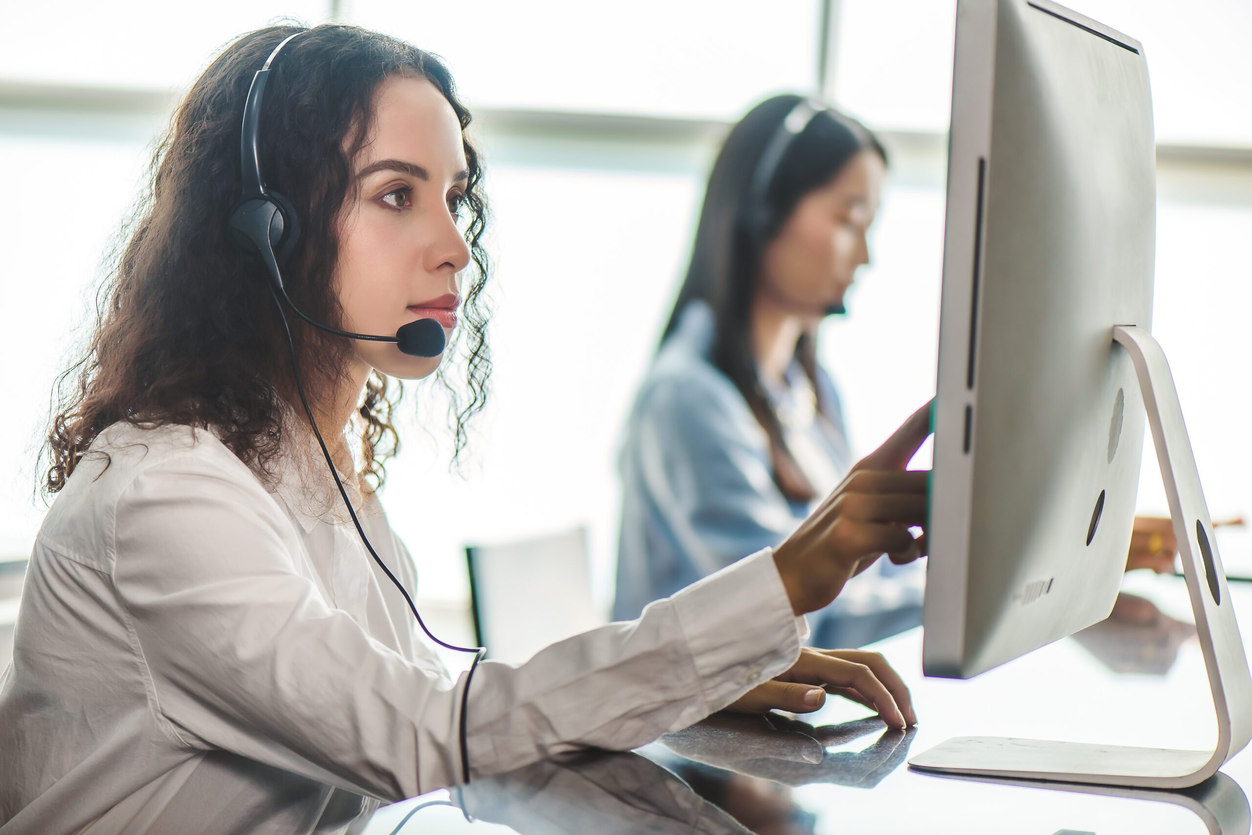 emergency dispatcher wearing a headset working at a computer