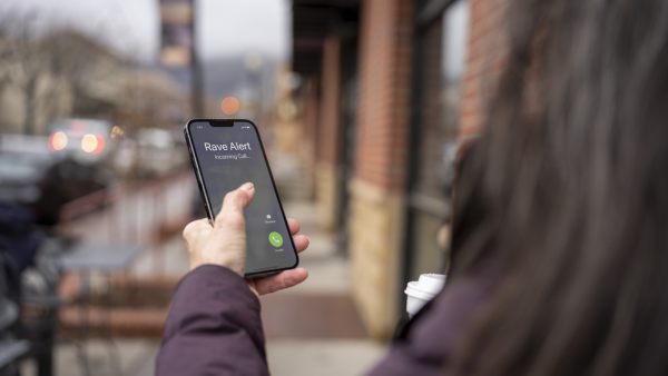 Woman holding phone with Rave Alert calling on screen