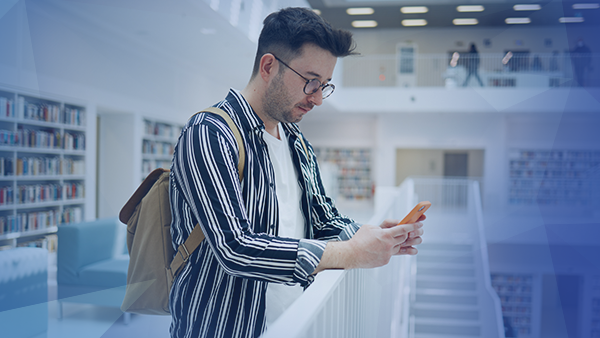 College student in library looking at message on cell phone